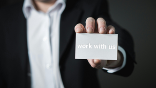 Man holding a business card with the words 'work with us' on it 
