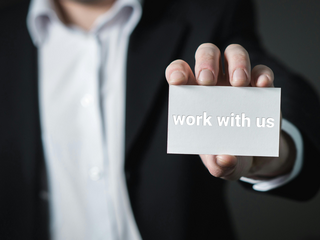 Man holding a business card with the words 'work with us' on it 
